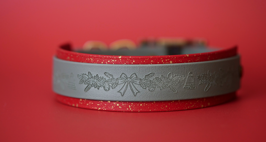 Green and red embossed Christmas dog collar with gold hardware photographed on a plain red background