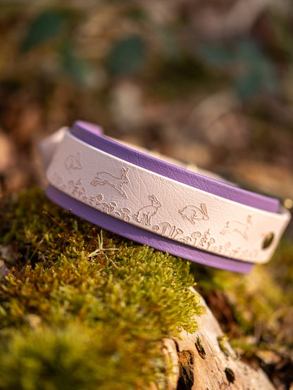 Wild Hare hound dog collar resting on moss in woodland showing embossed hare design detail