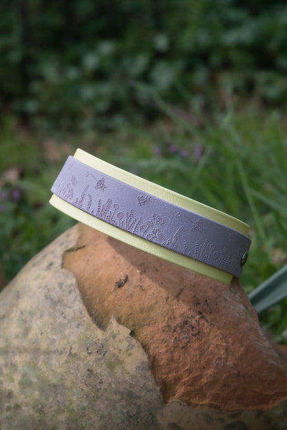 Lilac bee themed dog collar displayed on ceramic pot in garden setting