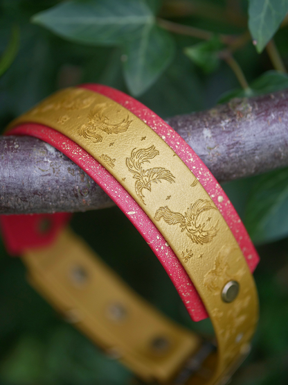 Phoenix in flight embossed dog collar resting on woodland branch showing gold Biothane and speckled stars